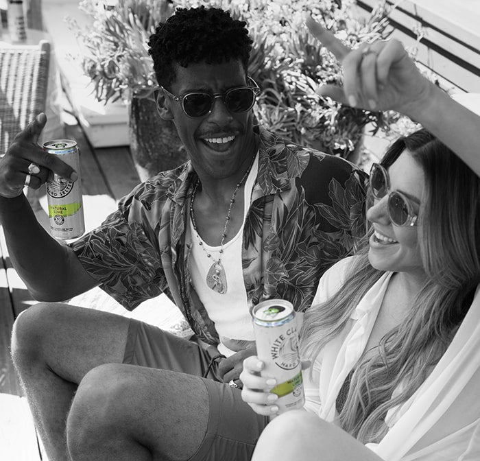 Two friends sitting together enjoying a Natural Lime WHITE CLAW®