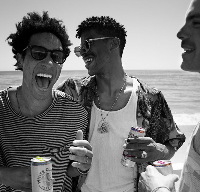 Three friends enjoying drinks by the beach