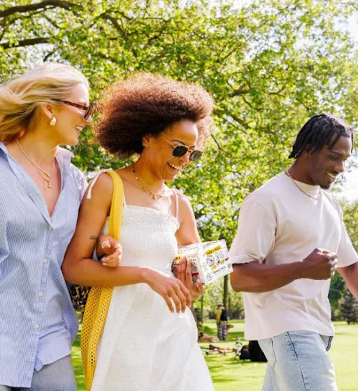 Three friends holding a white Claw Variety Pack outdoors