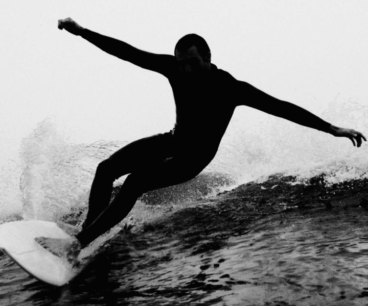 shadowed figure surfing in ocean 
